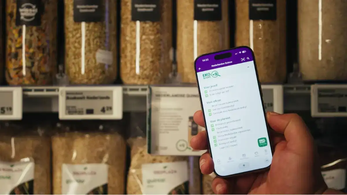 Scan het product in de winkel en bekijk de Ekoscope Persoon in de Ekoplaza-winkel scant de quinoa van Wisselwaar bij het schap en bekijkt de Ekoscope