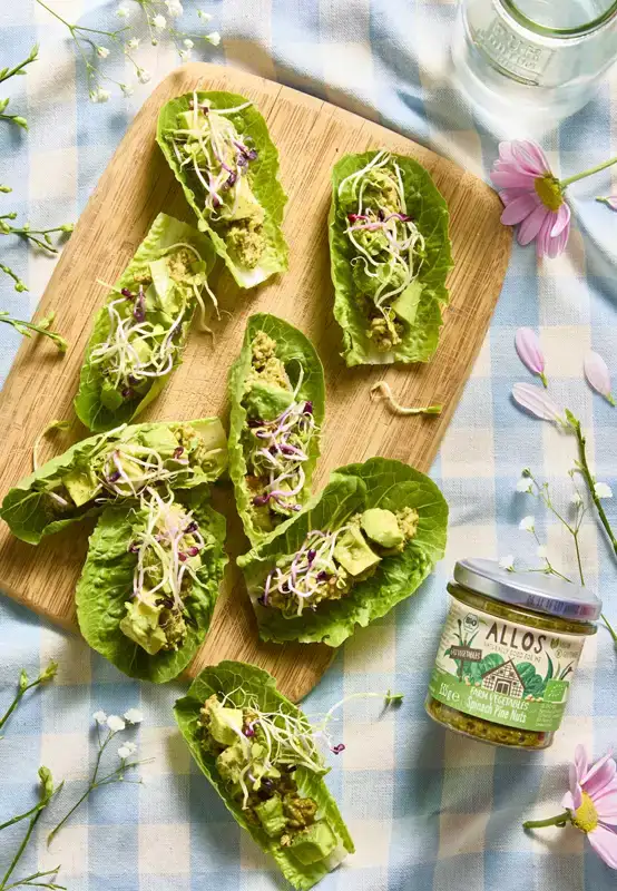 Een houten serveerplank met flatbread, besmeerd met tzatziki en belegd met zoete aubergine