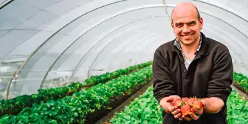 Teler Johan Tielen met biologische aardbeien in zijn hand op zijn bedrijf