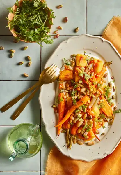 Een houten serveerplank met flatbread, besmeerd met tzatziki en belegd met zoete aubergine